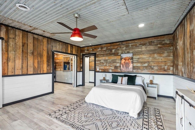 unfurnished bedroom with light wood-type flooring, wooden ceiling, ceiling fan, and wood walls