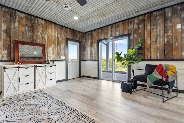 sitting room featuring ceiling fan, wood walls, light wood-type flooring, and wooden ceiling