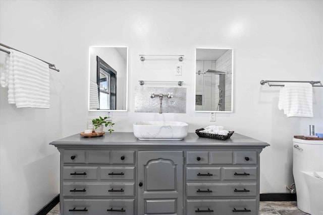 bathroom featuring a shower with door, vanity, and toilet