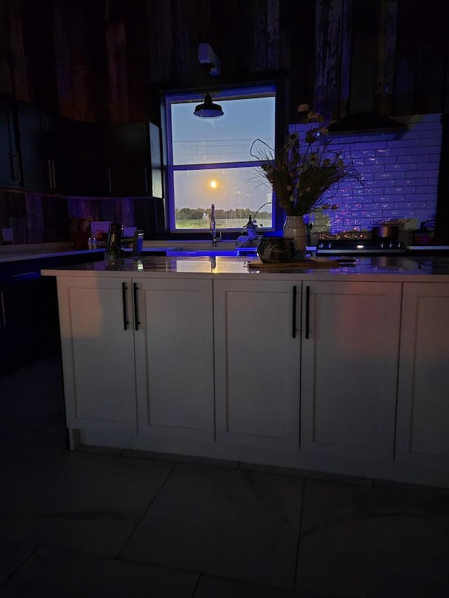 kitchen with range hood, stovetop, sink, white cabinets, and decorative backsplash