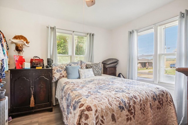 bedroom featuring ceiling fan, hardwood / wood-style floors, and multiple windows