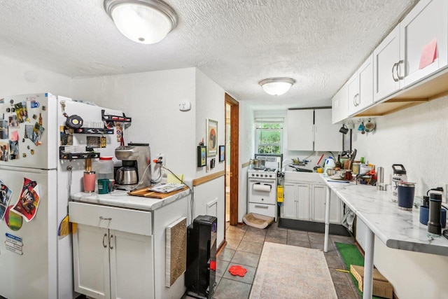 kitchen featuring light tile patterned floors, white cabinetry, a textured ceiling, and white fridge