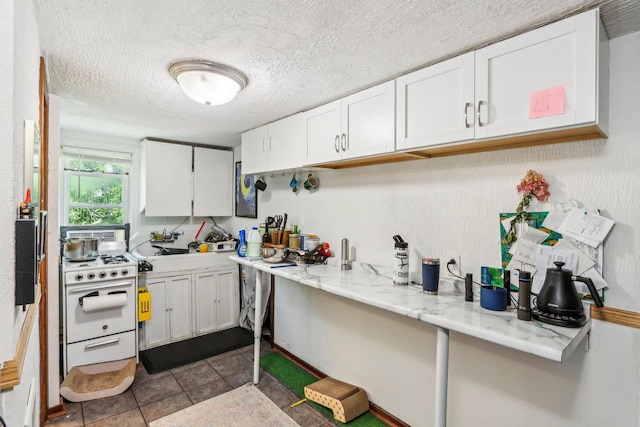 kitchen with light stone counters, white cabinets, a textured ceiling, and white gas range oven