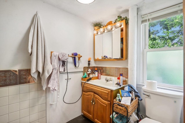 bathroom featuring tile walls, vanity, and toilet