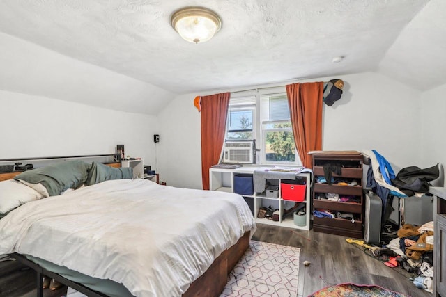 bedroom with cooling unit, hardwood / wood-style flooring, vaulted ceiling, and a textured ceiling