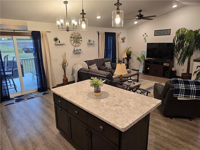 kitchen featuring ceiling fan with notable chandelier, wood-type flooring, lofted ceiling, and a center island