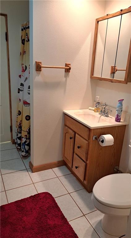 bathroom featuring tile patterned floors, vanity, toilet, and walk in shower