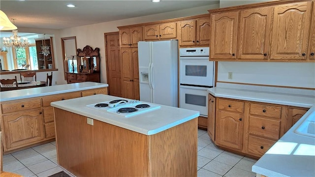 kitchen featuring white appliances, a center island, a notable chandelier, and light tile patterned flooring