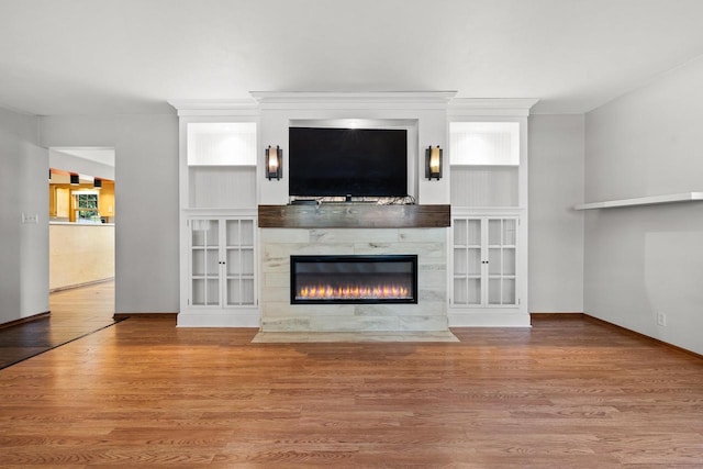 unfurnished living room featuring light wood-type flooring, a high end fireplace, and crown molding