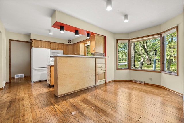 kitchen featuring kitchen peninsula, light hardwood / wood-style floors, and white appliances