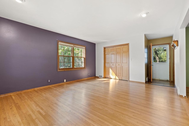 unfurnished bedroom featuring light wood-type flooring, a closet, and multiple windows