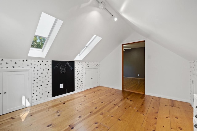 bonus room with wood-type flooring and lofted ceiling with skylight