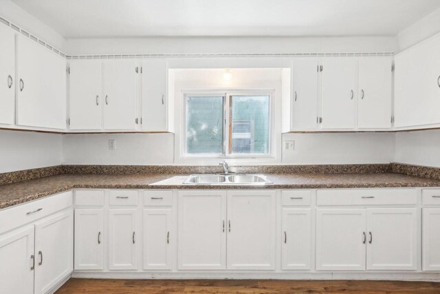 kitchen with hardwood / wood-style floors, white cabinetry, and sink