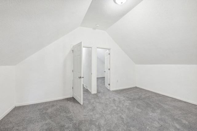 bonus room with a textured ceiling, lofted ceiling, and light colored carpet