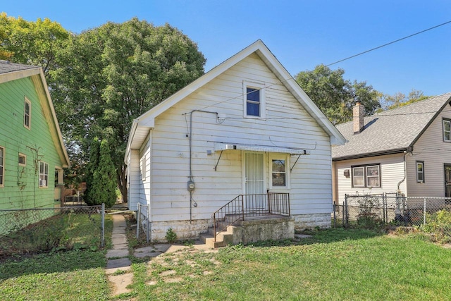 rear view of property featuring a lawn