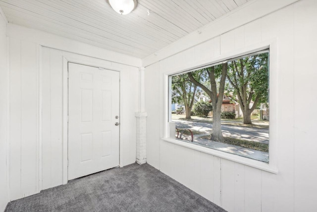 unfurnished room featuring wooden ceiling, wooden walls, and dark colored carpet