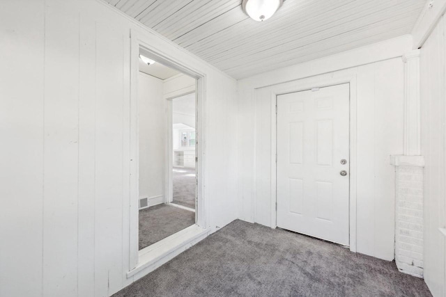 corridor with wood ceiling, wooden walls, and carpet flooring