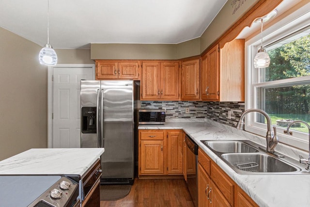 kitchen featuring appliances with stainless steel finishes, decorative light fixtures, sink, dark hardwood / wood-style flooring, and decorative backsplash