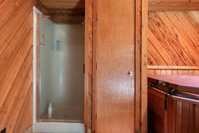 bathroom featuring an enclosed shower and wood walls