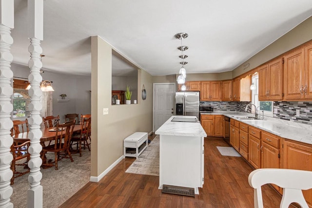 kitchen featuring sink, backsplash, stainless steel appliances, a kitchen island, and decorative light fixtures