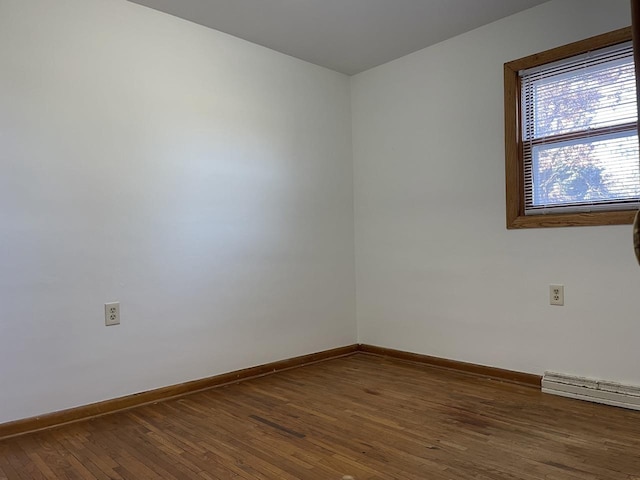 unfurnished room with baseboard heating and dark hardwood / wood-style floors