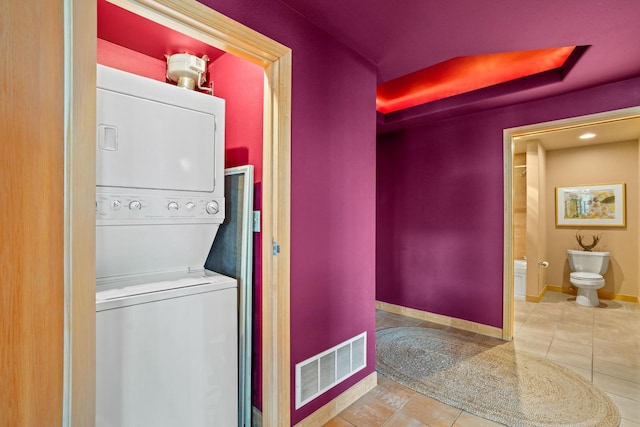 washroom with stacked washer / drying machine and tile patterned floors