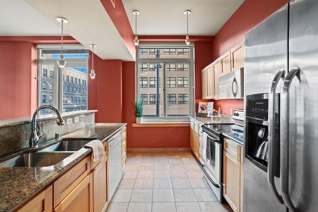 kitchen featuring hanging light fixtures, light tile patterned floors, sink, stainless steel appliances, and dark stone countertops