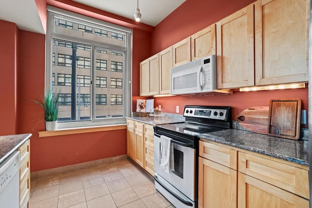 kitchen with stainless steel appliances, dark stone countertops, light brown cabinetry, and light tile patterned floors