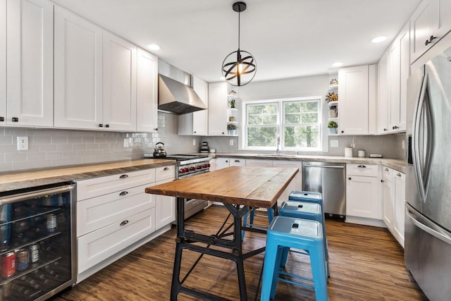 kitchen with dark wood-type flooring, beverage cooler, white cabinetry, wall chimney exhaust hood, and stainless steel appliances