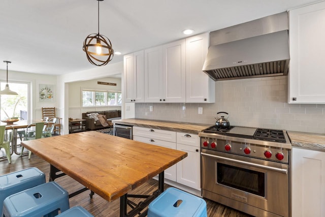 kitchen with wall chimney exhaust hood, white cabinets, pendant lighting, and luxury range