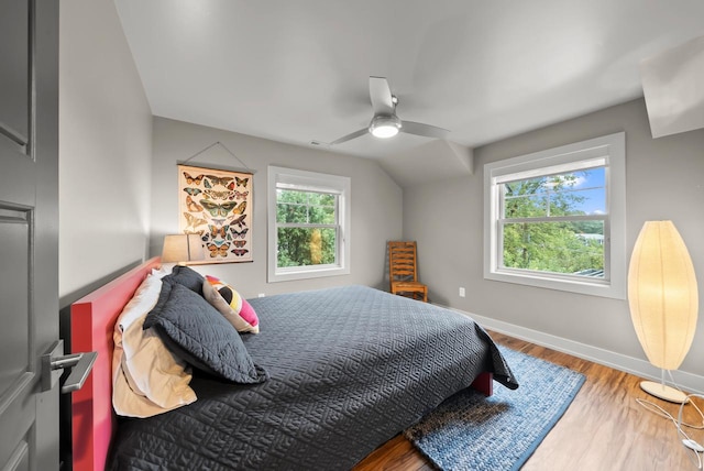 bedroom featuring ceiling fan, wood-type flooring, vaulted ceiling, and multiple windows