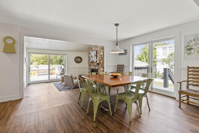 dining space featuring hardwood / wood-style flooring, a healthy amount of sunlight, and a stone fireplace