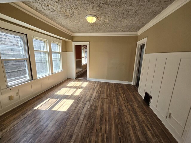 empty room with ornamental molding, a textured ceiling, and dark hardwood / wood-style flooring