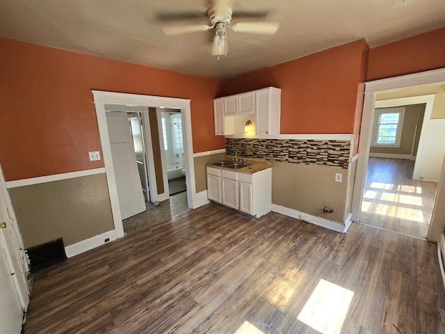 kitchen featuring ceiling fan, sink, backsplash, white cabinetry, and dark hardwood / wood-style flooring