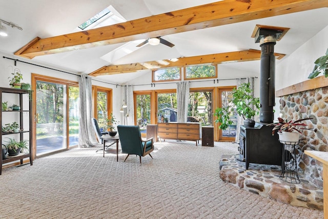 sunroom / solarium featuring plenty of natural light, ceiling fan, lofted ceiling with skylight, and a wood stove