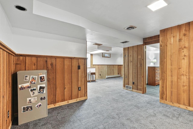 bonus room with a baseboard radiator, wood walls, and carpet