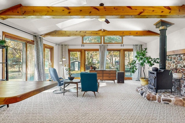 sunroom / solarium featuring ceiling fan, lofted ceiling with skylight, and a wood stove