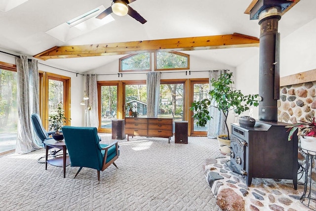 sunroom with vaulted ceiling with skylight, ceiling fan, and a wood stove