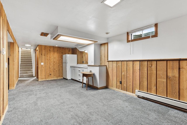 interior space featuring wood walls, light colored carpet, and baseboard heating