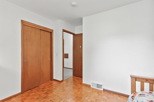 unfurnished bedroom with a closet and light parquet flooring