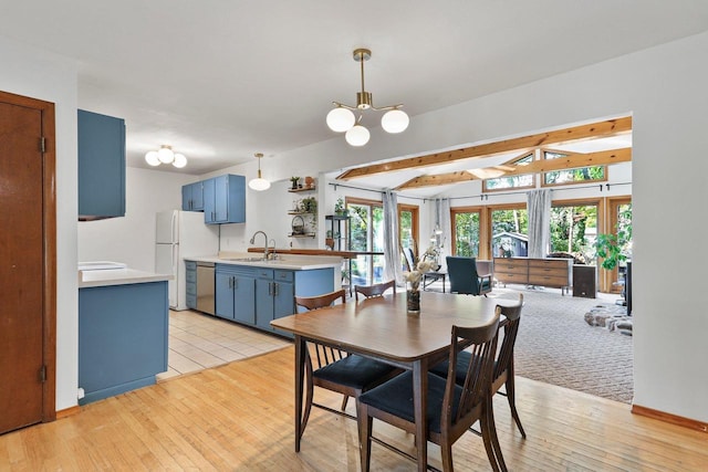 dining space with beamed ceiling, light wood-type flooring, a chandelier, and sink