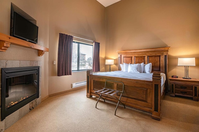 carpeted bedroom with baseboard heating and a tile fireplace