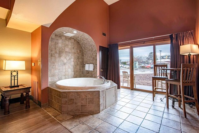 bathroom with tiled bath and a high ceiling