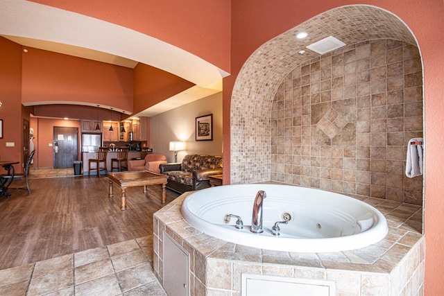 bathroom featuring tile walls, hardwood / wood-style flooring, and a relaxing tiled tub