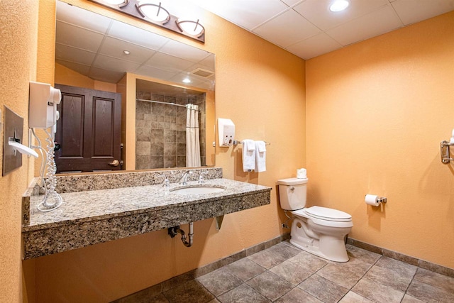 bathroom featuring tile patterned flooring, a paneled ceiling, toilet, sink, and a shower with curtain