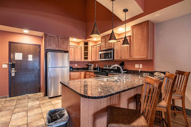 kitchen with stainless steel appliances, dark stone countertops, kitchen peninsula, and a breakfast bar area