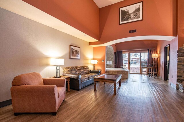 living room with wood-type flooring and a towering ceiling