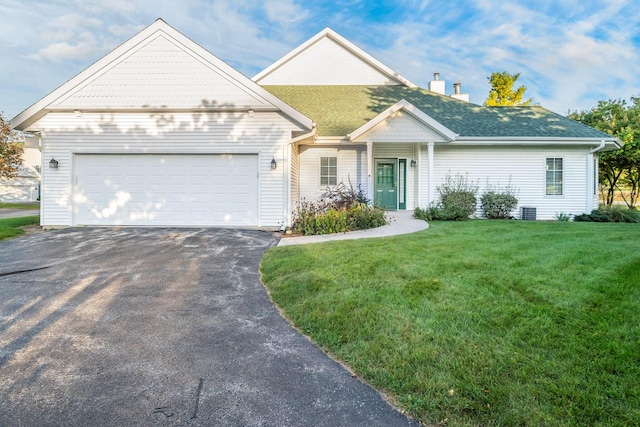 view of front of house with cooling unit, a garage, and a front lawn