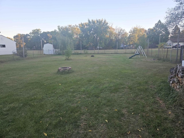 view of yard with a storage unit, a playground, and a fire pit