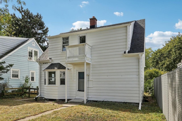 rear view of house featuring a yard and a balcony